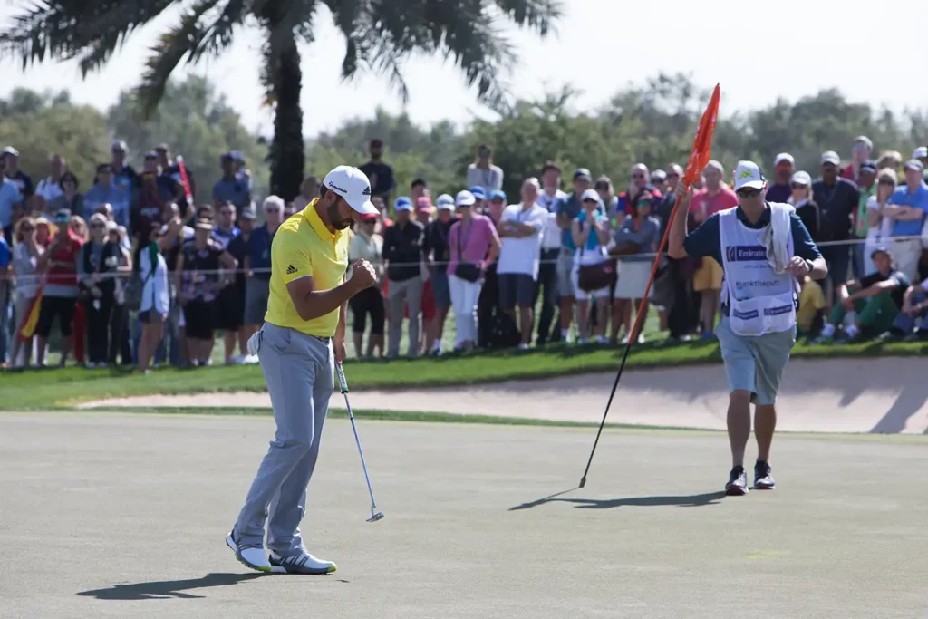 Sergio Garcia gör en seger gest på en golf green med stor publik runt om.