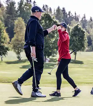 Två personer som gör high five på en golfgreen